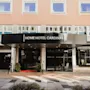 Kutsuva hotellin sisäänkäynti, jossa kyltti HOME HOTEL CARDINAL. Punainen matto ja ruukkukasvit koristavat sisäänkäyntiä.