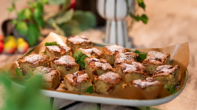 Et fat med nybakte, sukkerdryssete kakebiter pyntet med mynteblader, klare til å nytes.