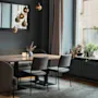 Et moderne spiseområde med et langt trebord, komfortable sitteplasser og varm belysning, med planter ved et stort vindu.