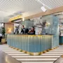 To ansatte som står bak en moderne hotellresepsjon og ønsker gjester velkommen.