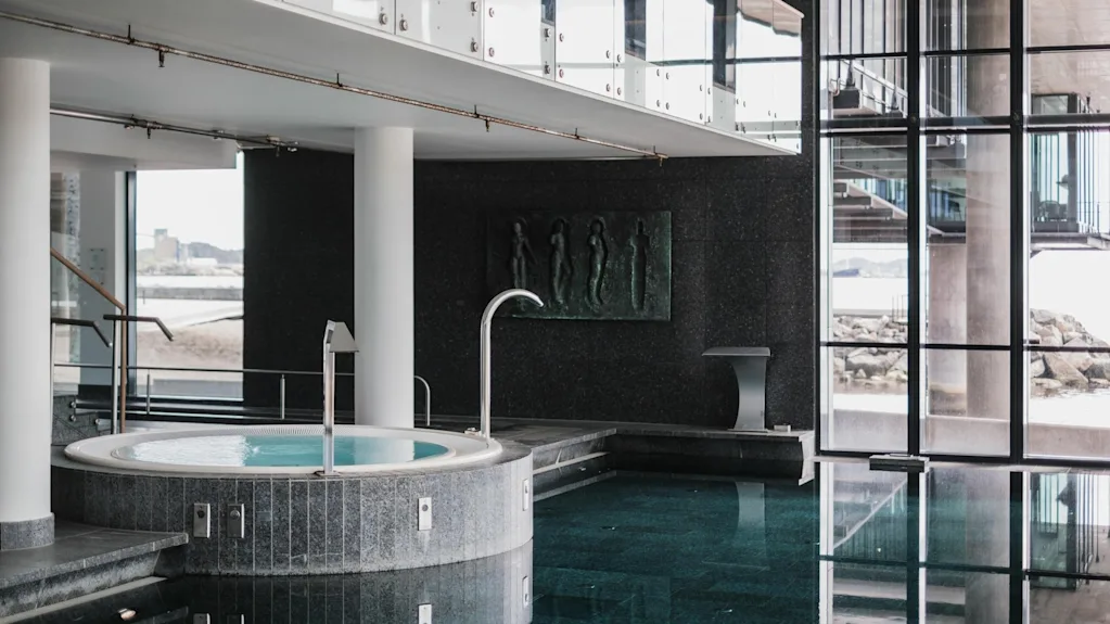 Indoor pool and hot tub at Farris Bad in Larvik, with large windows overlooking the sea and a modern, spacious design.