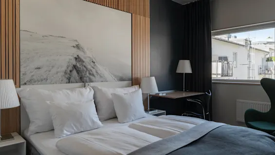 A modern hotel room at Clarion Hotel Sign with a comfortable bed, a desk, and a window offering a view outside.