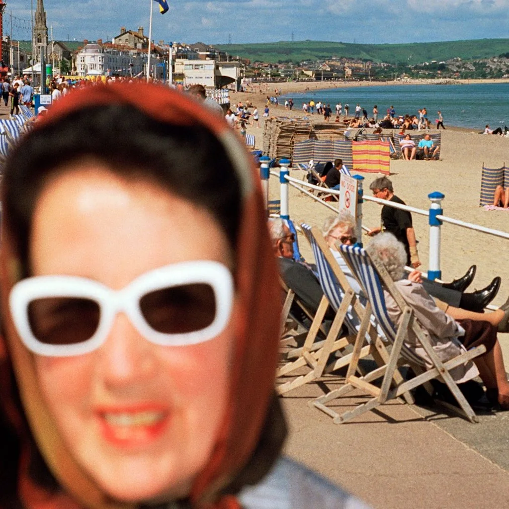 Martin Parr: Livlig strandscen med folk som njuter av solen, promenerar och kopplar av. BEACH CONTROL POINT 4 DECK CHAIR HIRE.