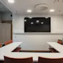 A bright conference room at Home Hotel Uppsala featuring a U-shaped table arrangement, comfortable chairs, and a large display.