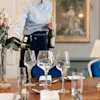 En servitør heller vin i et glass ved et vakkert dekket spisebord på Jørgensens Hotel – Restaurant Eydes.