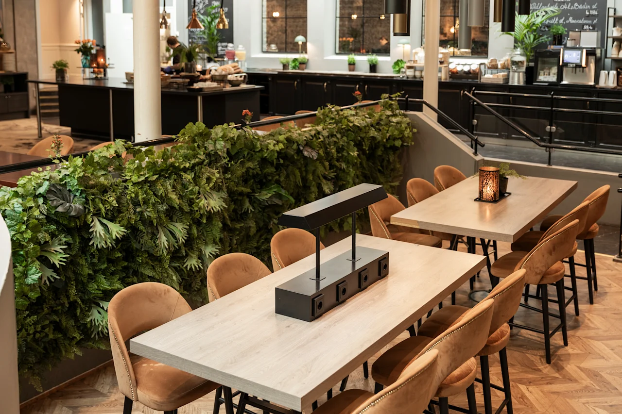 Home Hotel Grand Bodø: A welcoming hotel dining area with plush seating, a vibrant green wall, and a buffet. Text: alltid inkludert i prisen, frokost.