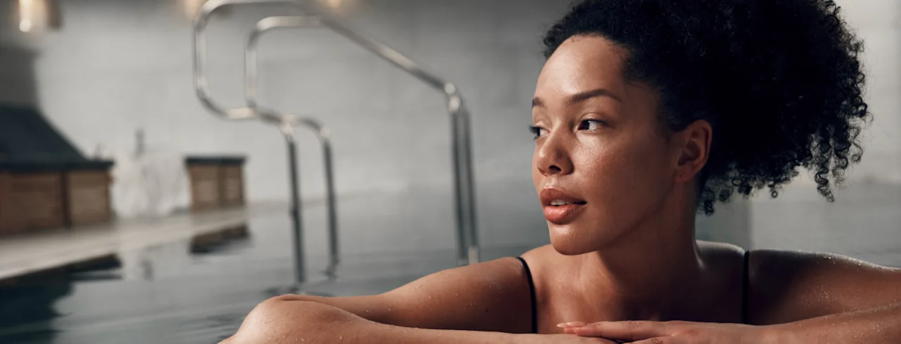 A woman relaxing in a calm indoor pool at a modern spa.