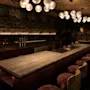En dunkelt upplyst bar med en lång disk, barstolar och sfäriska taklampor, vilket skapar en mysig och inbjudande atmosfär.