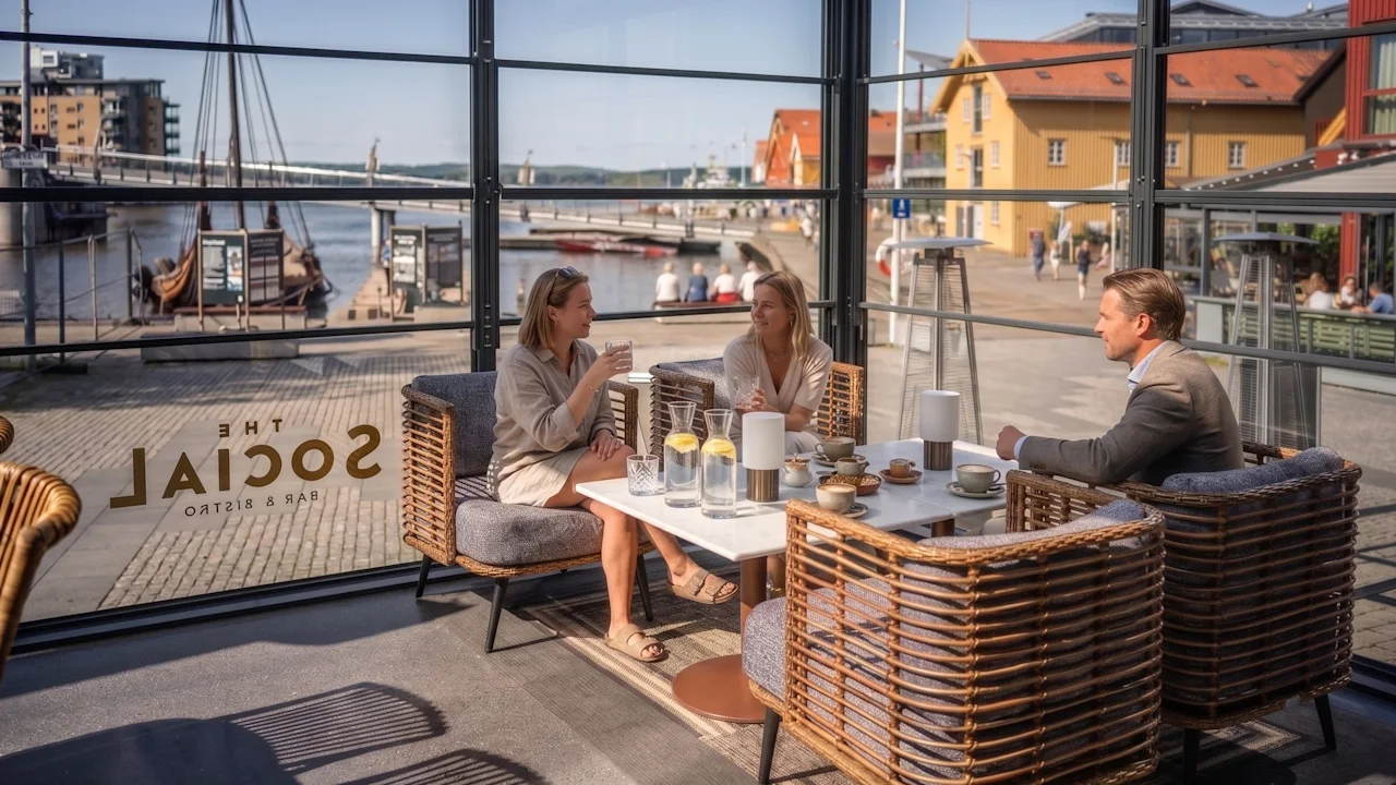 People enjoying drinks and conversation at a bright waterfront restaurant table.