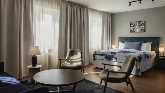 Ett inbjudande hotellrum med en bekväm säng och en separat loungeavdelning, perfekt för avkoppling.