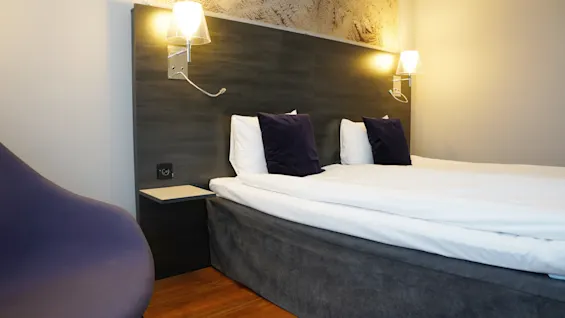 Viihtyisä hotellihuone Quality Hotel Sundsvallissa, jossa on sänky, yöpöytä ja mukava tuoli.
