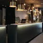 Et indbydende hotelreceptionsområde med en moderne disk med varm belysning, messingpendellamper og et naturinspireret vægmaleri.