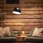 To lænestole med puder vender mod hinanden, adskilt af et lille bord med en plante og lampe. En buet gulvlampe lyser op mod en trævæg.
