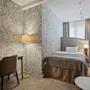 A welcoming hotel room featuring a comfortable bed, a functional desk area, and soft lighting, with decorative wallpaper.