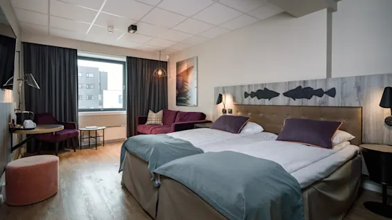 Et familierom for fire personer på Quality Hotel Grand Tromsø, med to senger, en sofa og et komfortabelt sitteområde.