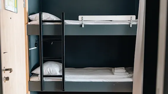 Bunk bed in a modern hotel room with dark walls and a ladder.