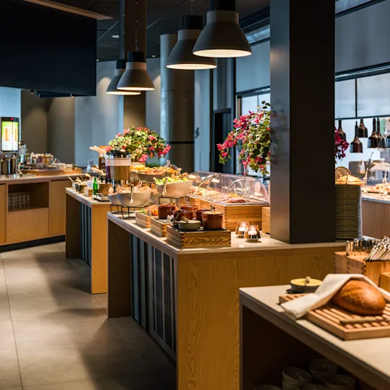 En velfylt frokostbuffé med ulike matretter, drikke og ferskt brød i en moderne restaurantinnredning.