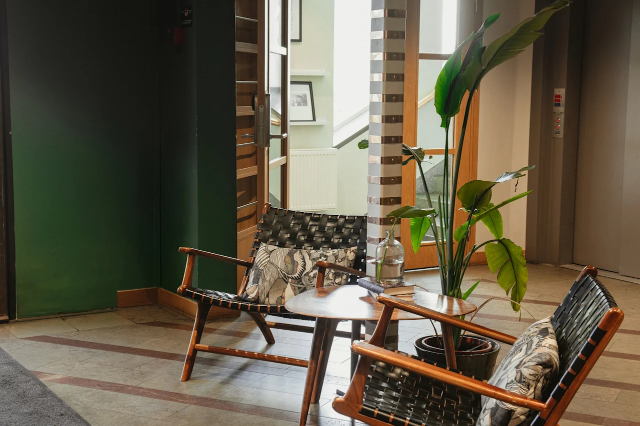 A welcoming seating area with two chairs, a small table, and a large plant, suggesting a comfortable waiting space at Home Hotel Uppsala.
