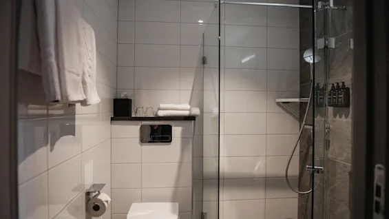 Et rent og moderne bad med toalett, friske håndklær og en romslig dusj med toalettartikler.