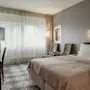 Ett mysigt hotellrum med en bekväm säng, en skrivbordshörna och en sittgrupp vid ett stort fönster.