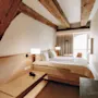 Ett mysigt hotellrum med en bekväm säng, synliga träbjälkar och en ljus balkongutsikt, för en avkopplande vistelse.
