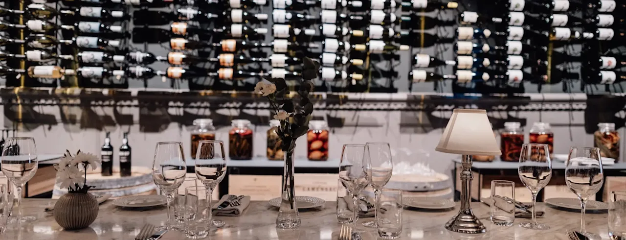 Jørgensens Hotel – Restaurant Eydes – Vinbar. Et elegant dekket bord for et måltid, med en stor vinsamling.