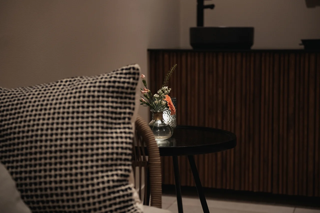 Cozy interior at Home Hotel Uppsala with a patterned pillow, a small table holding a vase of flowers, and a wooden cabinet.