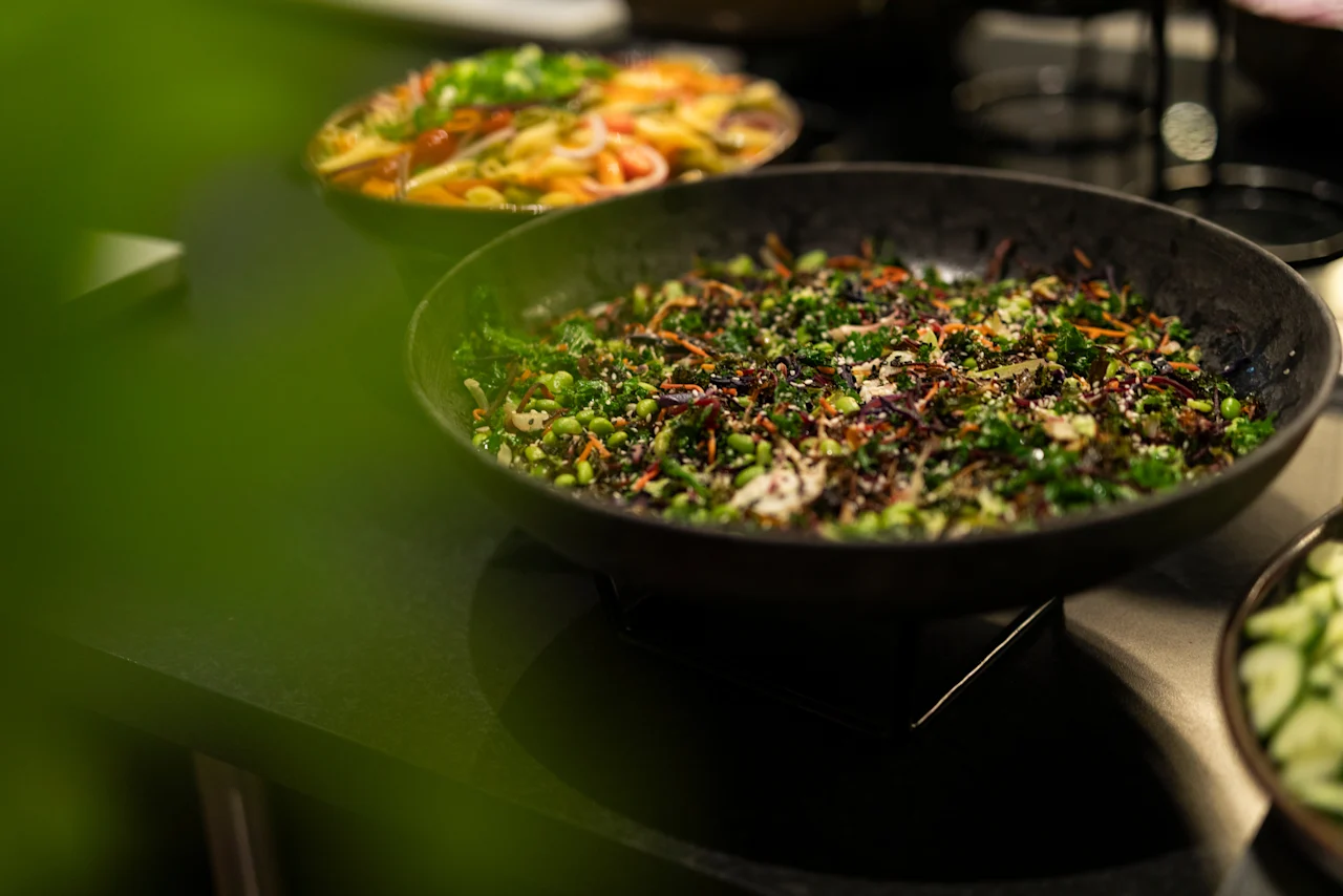 A close-up of a fresh, colorful salad bar at Home Hotel Grand Bodø, featuring a green salad with edamame and sesame seeds.