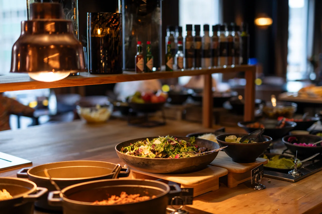 En varm og indbydende buffet med en frisk salat, forskellige varme retter, krydderier og en etiket for lime.