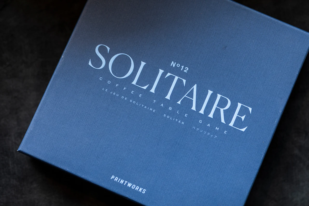 Sininen laatikko Solitaire-kahvipöytäpeliä varten, tekstillä Solitaire No 12 Coffee Table Game useilla kielillä.