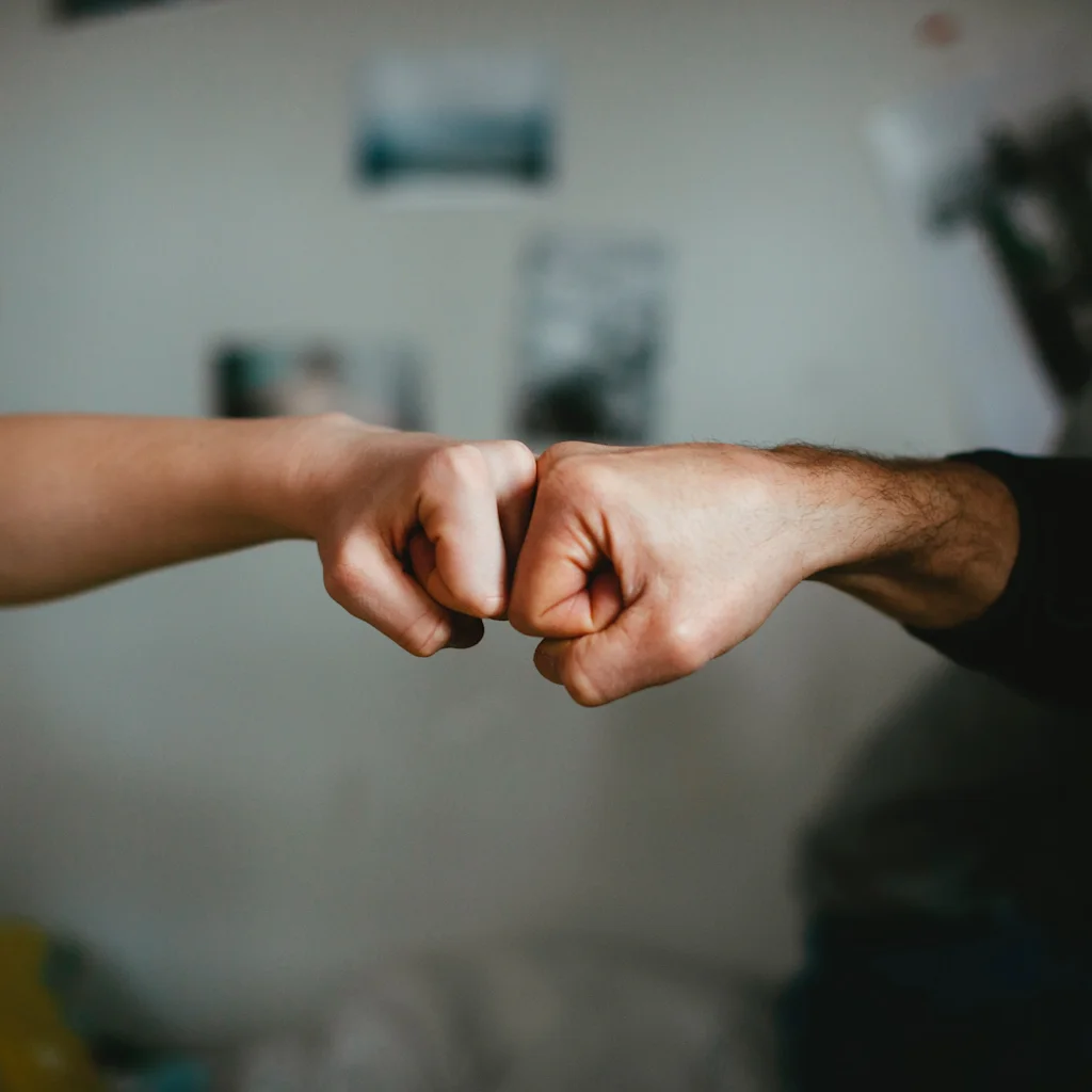 Två personer som gör en fist bump, vilket symboliserar överenskommelse, hälsning eller lagarbete.