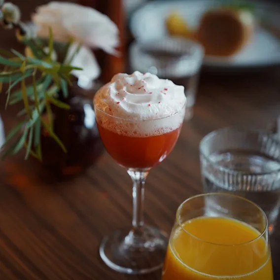 Herkullinen punainen juoma kermavaahdolla, tarjoiltuna appelsiinimehun ja veden kera. Juoma Clarion Hotel Helsinki Airportissa.