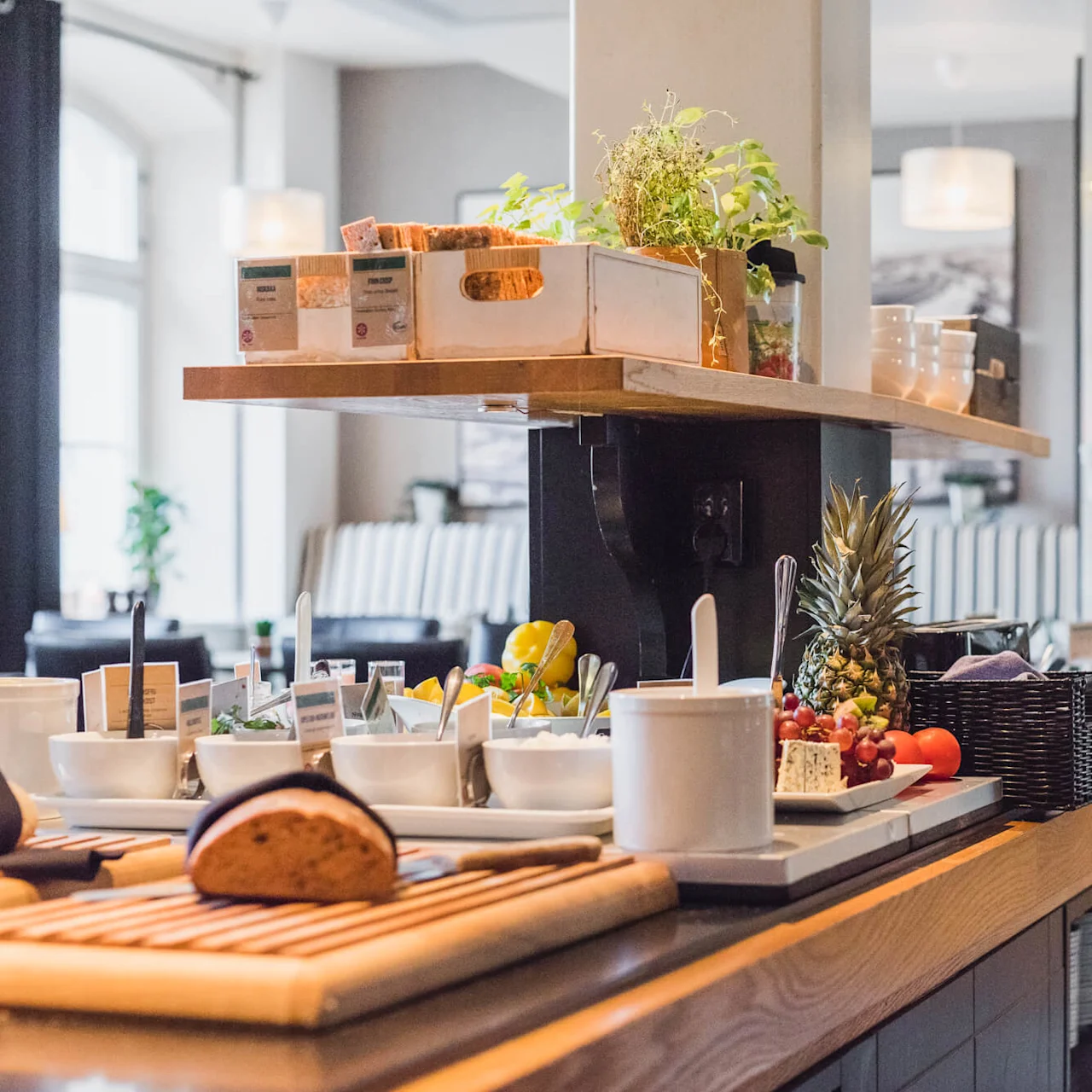 A breakfast buffet with various food items displayed on wooden counters inside a modern dining area with soft lighting.