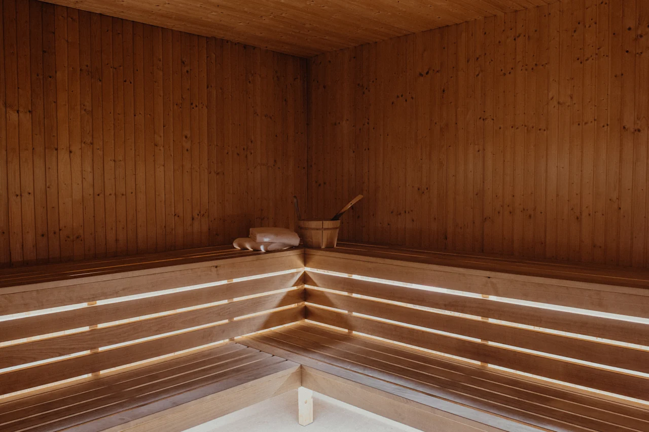 En varm og indbydende træsauna med bænke, en spand og en øse, klar til en afslappende oplevelse.