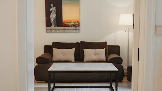 Et komfortabelt siddeområde på Home Hotel Norre Park i Halmstad, med en sofa, sofabord og et naturskønt maleri.