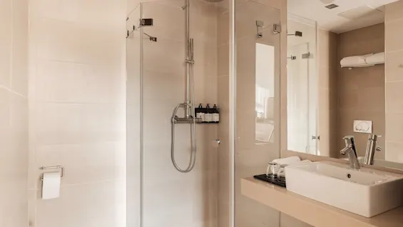 A modern and clean bathroom at Farris bad, featuring a spacious glass shower and a sleek sink area.