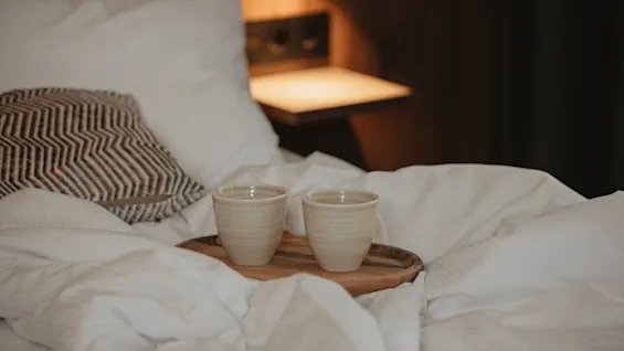 En varm og innbydende seng med to kopper på et brett, perfekt for en fredelig start på dagen.