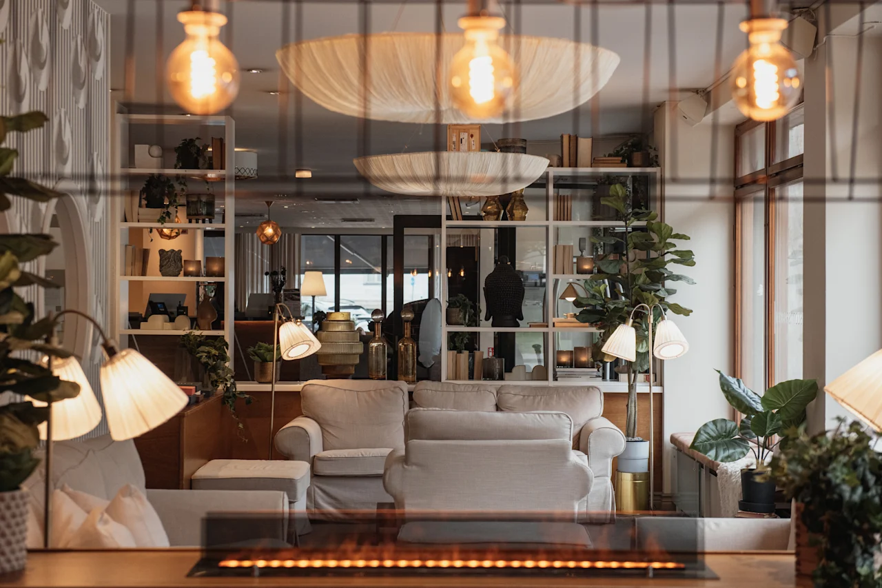 A warm and inviting lounge area with comfortable sofas, plants, and soft lighting, featuring a modern fireplace.