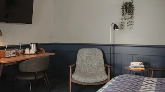 Ett mysigt hotellrum med skrivbord, bekväma sittplatser och en säng, designat för avkoppling och arbete.