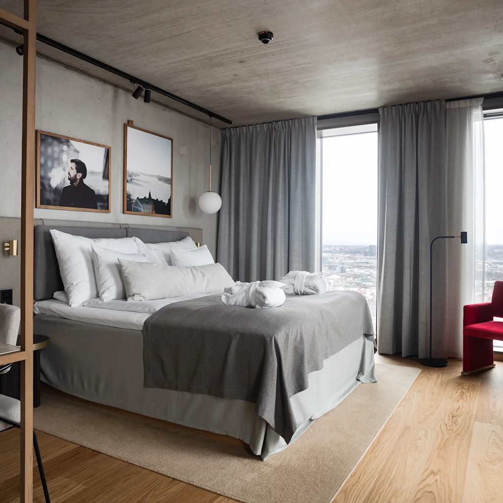 Mukava ja tyylikäs hotellihuone, joka on suunniteltu rentoutumiseen, ja jossa on suuri sänky, kaupunkinäköala ja viihtyisä oleskelualue.