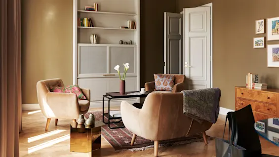 To beige lenestoler vender mot et salongbord med blomster i en koselig stue. En bokhylle og kunstverk pryder rommet, med lys som strømmer inn gjennom et vindu.