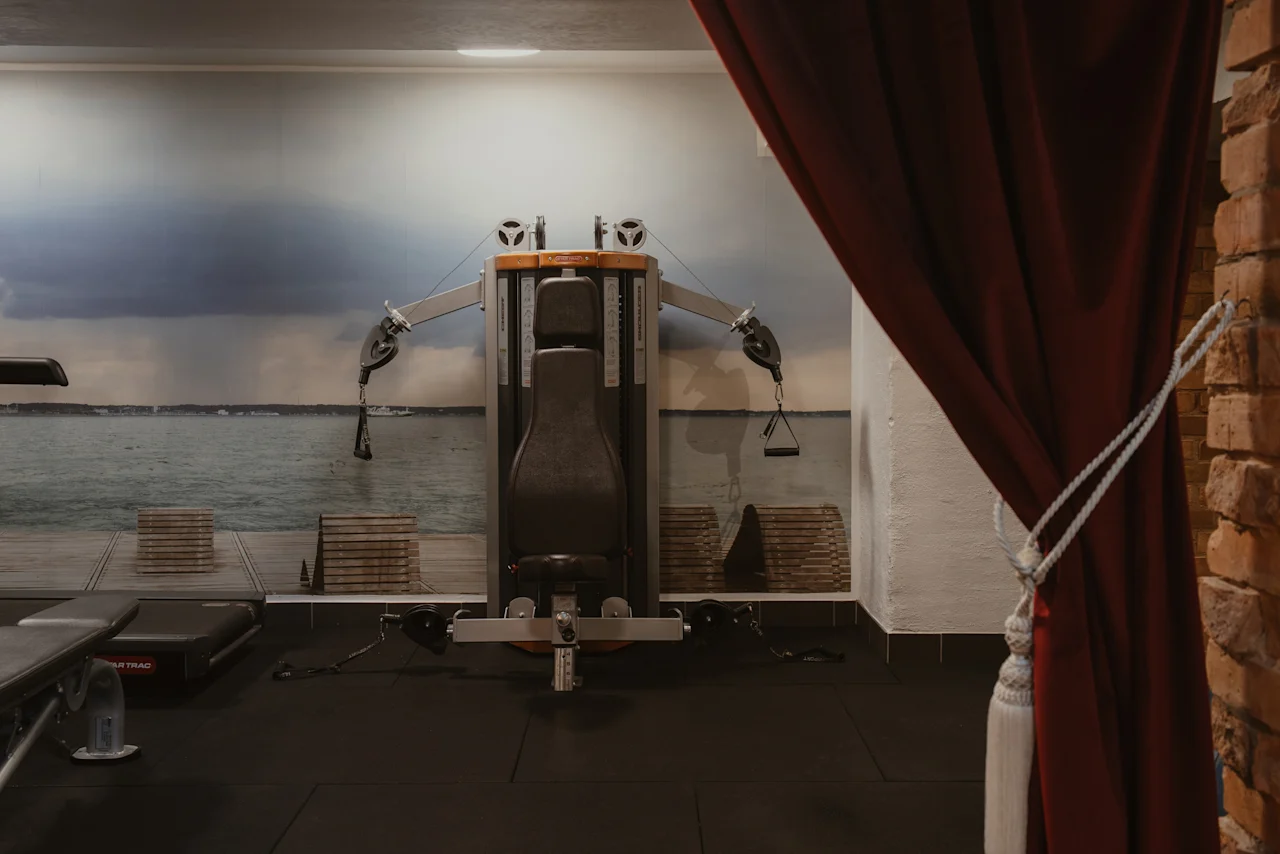Ett inbjudande gym på Home Hotel Grand, Helsingborg, med träningsutrustning mot en naturskön havsmålning.