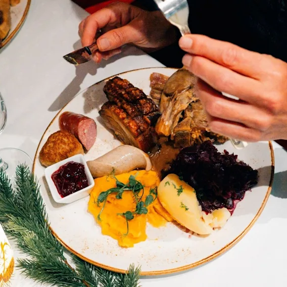 En tallerken fylt med tradisjonell norsk julemat som ribbe, pinnekjøtt, medisterkake, rødkål og poteter.