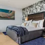 Et komfortabelt og stilfullt soverom på Quality Hotel Ulstein, med en stor seng, et naturskjønt maleri og en aksentvegg med steinmønster.