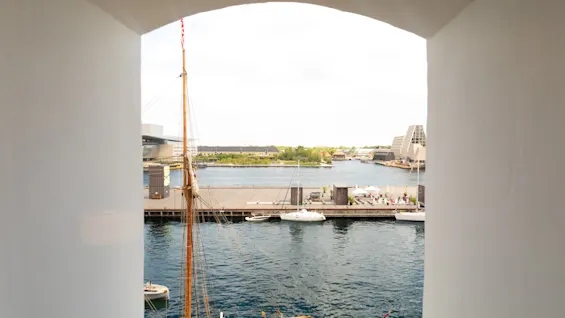 Utsikt över en hamn med båtar och byggnader inramad av en vit fönsterbåge.
