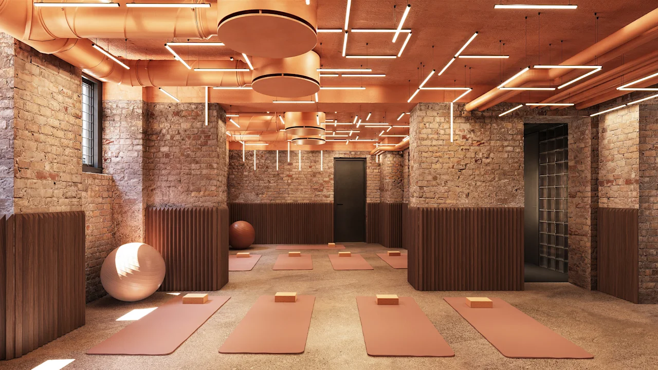 Modern yoga studio with brick walls, warm lighting, and mats laid out on the floor.