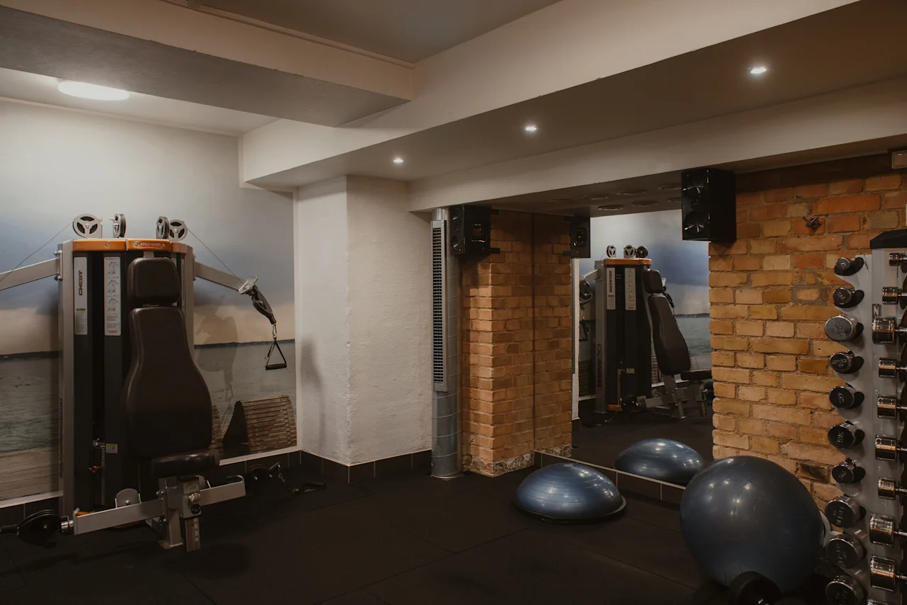 Ett välutrustat gym på Home Hotel Grand, Helsingborg, med olika träningsmaskiner, vikter och balansredskap.