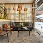 Cozy hotel lobby lounge with a dark sofa, brown leather armchairs, a coffee table, and hanging wicker lamps by a window.