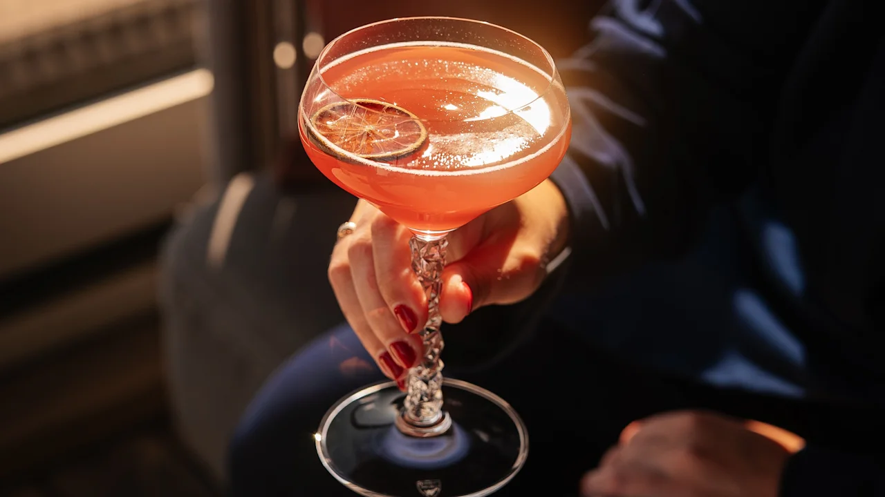 Henkilö pitelee eloisaa cocktailia sitruskoristeella Clarion Hotel Signin baarissa.