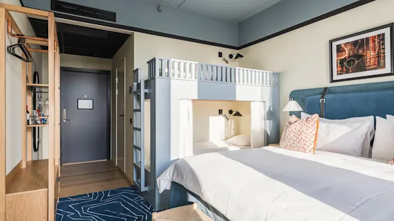 Et lyst og moderne hotelværelse på Hernö Gin Hotel med en stor seng og en køjeseng, perfekt til et familieophold.